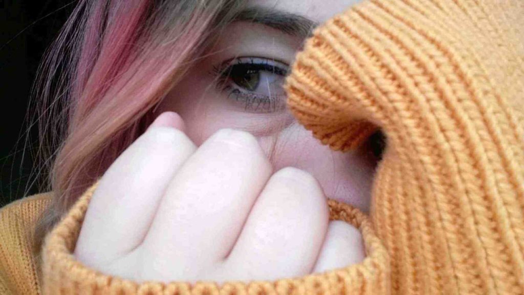 Woman with hands up, concealing her face
